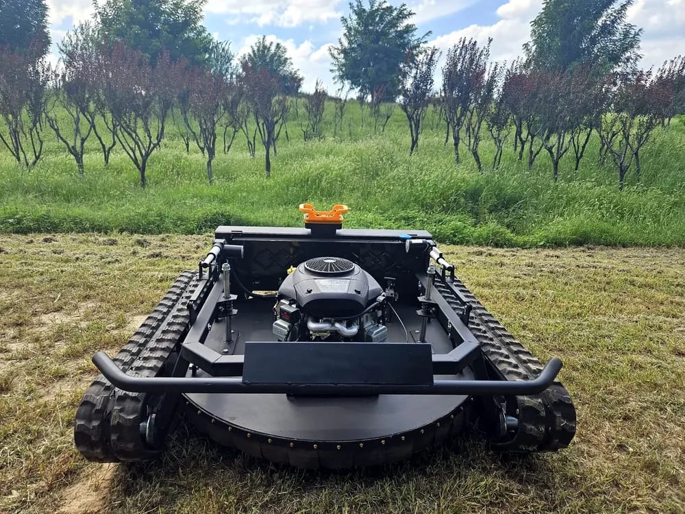 Tracked mower photographed between orchard trees